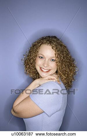 Stock Photo - Portrait of smiling young adult Caucasian woman on blue background.. Fotosearch
