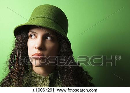 Stock Image - Young Caucasian woman on green background wearing green clothing and hat.. Fotosearch
