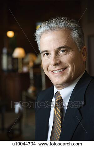 Picture - Caucasian prime adult male businessman in hotel lobby.. Fotosearch