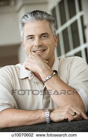 Stock Image - Caucasian prime adult male sitting at table.. Fotosearch