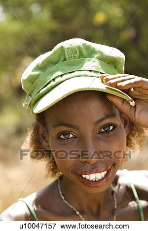 Stock Photo - MId-adult Black female with hand on cap and making eye contact.. Fotosearch