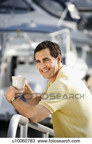 Portrait of Caucasian mid-adult male holding coffee cup at harbor looking at camera. View Large Photo Image Stock Image - Portrait of Caucasian mid-adult male holding coffee cup at harbor looking at camera. . Fotosearch