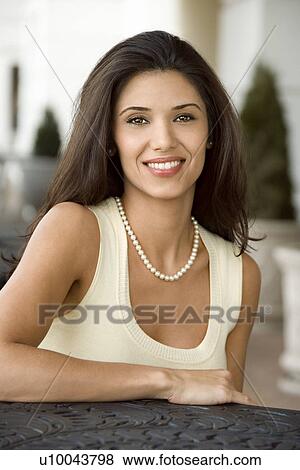 Stock Photo - Prime adult Hispanic female sitting at table.. Fotosearch