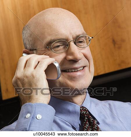 Smiling Caucasian middle-aged businessman sitting in office talking on cellphone. View Large Photo Image Stock Image - Smiling Caucasian middle-aged businessman sitting in office talking on cellphone.. Fotosearch