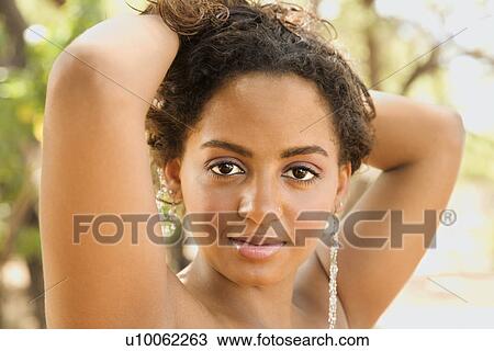 Stock Image - Young-adult Black woman with arms behind head holding hair up. . Fotosearch