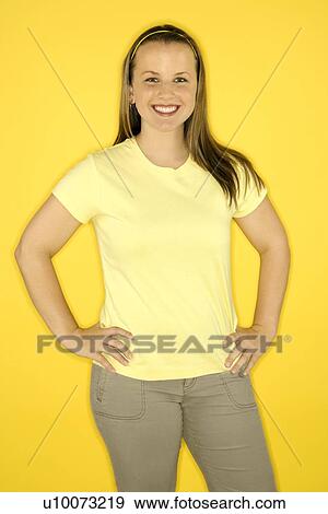 Stock Photo - Young adult female Caucasian standing smiling on yellow background.. Fotosearch