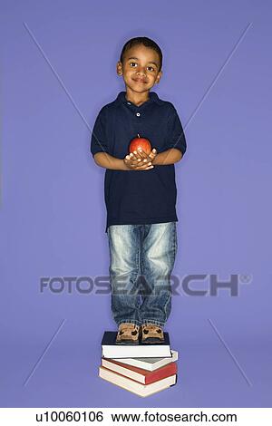 Stock Photograph - African American male child standing on stack of books.. Fotosearch