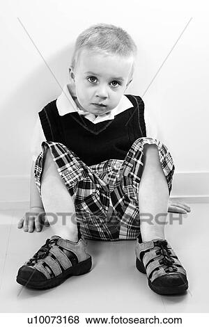 Stock Photo - Caucasian boy sitting on floor.. Fotosearch