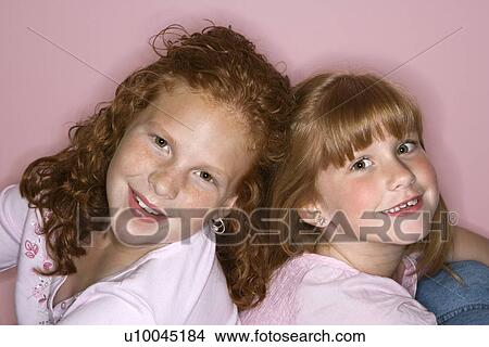 Picture - Caucasian female children sitting back to back.. Fotosearch
