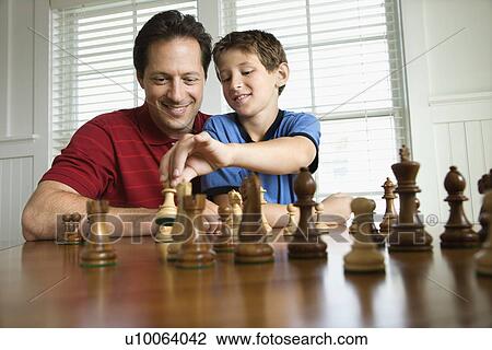 Stock Image - Caucasian mid-adult dad teaching chess to pre-teen boy.. Fotosearch
