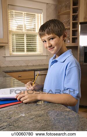 Caucasian pre-teen boy doing homework at kitchen counter looking at viewer and smiling. View Large Photo Image Stock Image - Caucasian pre-teen boy doing homework at kitchen counter looking at viewer and smiling.. Fotosearch
