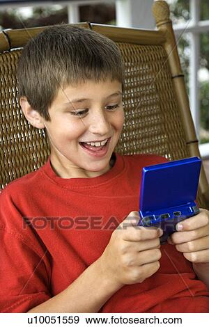 Caucasian pre-teen boy playing handheld video game and smiling. View Large Photo Image Stock Photo - Caucasian pre-teen boy playing handheld video game and smiling.. Fotosearch