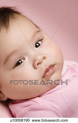 Stock Image - Close up of Asian babys face looking at viewer.. Fotosearch