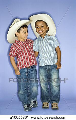 Stock Image - Hispanic and African American male child in cowboy hats.. Fotosearch