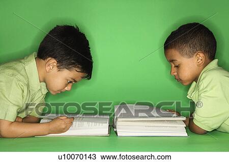 Stock Image - Hispanic and African American male child lying reading.. Fotosearch