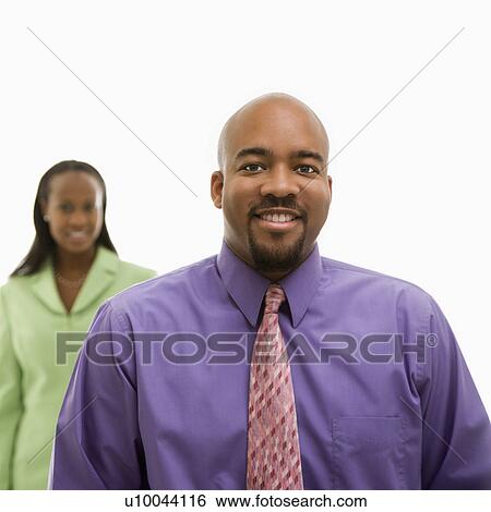 African-American businessman looking at viewer and smiling with businesswoman in background. View Large Photo Image Stock Photograph - African-American businessman looking at viewer and smiling with businesswoman in background.. Fotosearch