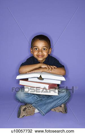Stock Image - African American male child sitting with books.. Fotosearch