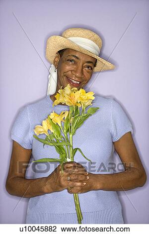 Stock Image - African American mature adult female with flowers.. Fotosearch