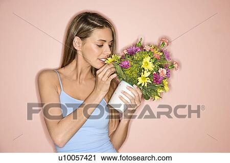 Caucasian mid-adult female holding pot of flowers and smelling them. View Large Photo Image Stock Image - Caucasian mid-adult female holding pot of flowers and smelling them.. Fotosearch