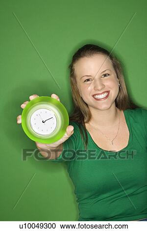 Caucasian young female adult holding out clock and smiling. View Large Photo Image Stock Image - Caucasian young female adult holding out clock and smiling.. Fotosearch