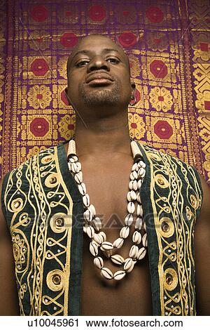 Low angle portrait of African-American mid-adult man wearing embroidered African vest and beads. View Large Photo Image Stock Image - Low angle portrait of African-American mid-adult man wearing embroidered African vest and beads.. Fotosearch