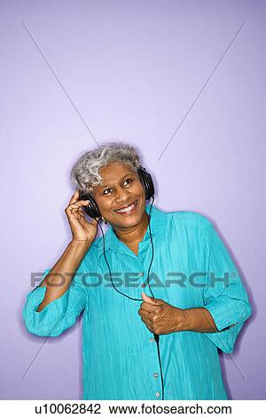 Mature adult African American female listening to headphones. View Large Photo Image Stock Image - Mature adult African American female listening to headphones.. Fotosearch
