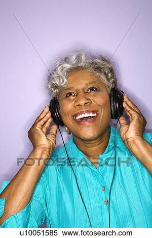 Stock Photography - Mature adult African American female listening to headphones.. Fotosearch
