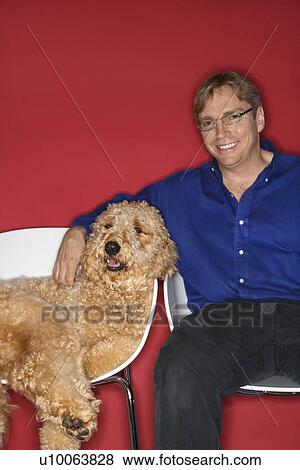 Stock Photo - Middle-aged Caucasian man with Goldendoodle dog.. Fotosearch