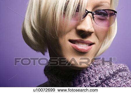 Stock Photo - Portrait of smiling blond young adult Caucasian woman on purple background wearing sunglasses and scarf.. Fotosearch