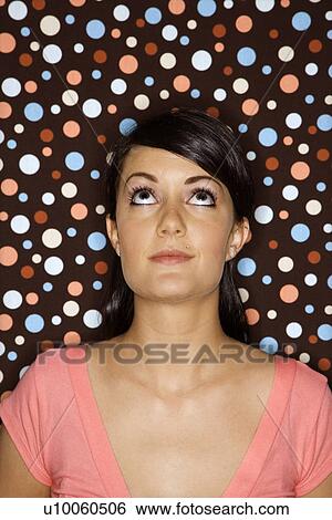 Stock Photograph - Young adult female Caucasian looking up on polka dot background.. Fotosearch