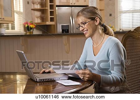 Caucasian mid-adult woman paying bills on laptop computer. View Large Photo Image Stock Photograph - Caucasian mid-adult woman paying bills on laptop computer.. Fotosearch