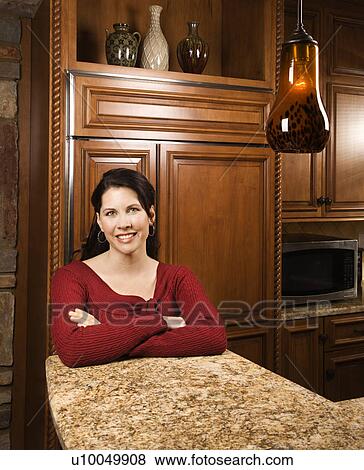 Caucasian woman leaning on marble kitchen counter smiling with arms crossed and looking at viewer. View Large Photo Image Stock Photo - Caucasian woman leaning on marble kitchen counter smiling with arms crossed and looking at viewer.. Fotosearch