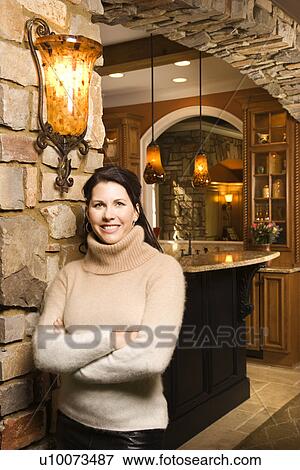 Caucasian woman standing in front of kitchen with arms crossed looking at viewer and smiling. View Large Photo Image Stock Photo - Caucasian woman standing in front of kitchen with arms crossed looking at viewer and smiling.. Fotosearch