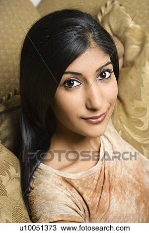 Close up portrait of Asian/Indian young woman sitting on couch. View Large Photo Image Stock Image - Close up portrait of Asian/Indian young woman sitting on couch.. Fotosearch