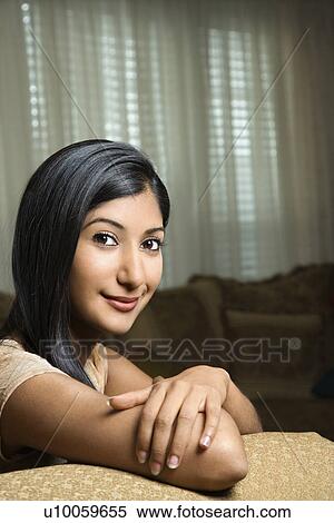 Close up portrait of Asian/Indian young woman sitting on couch. View Large Photo Image Stock Photography - Close up portrait of Asian/Indian young woman sitting on couch.. Fotosearch