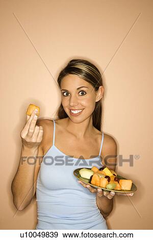 Stock Photo - Portrait of young adult woman holding up a piece of fruit. . Fotosearch