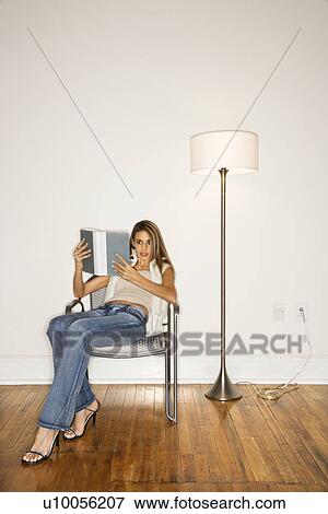 Portrait of young adult woman reading a book in silver chair next to floor lamp. View Large Photo Image Stock Photo - Portrait of young adult woman reading a book in silver chair next to floor lamp.. Fotosearch