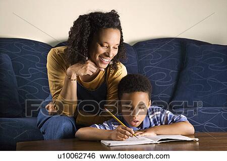 Portrait of young boy doing homework while mother looks over shouulder. View Large Photo Image Stock Photograph - Portrait of young boy doing homework while mother looks over shouulder.. Fotosearch