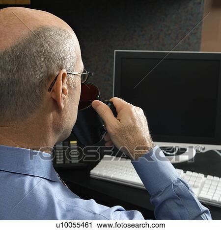 Back view of Caucasian middle-aged businessman drinking from coffee cup sitting at desk looking at computer. View Large Photo Image Stock Image - Back view of Caucasian middle-aged businessman drinking from coffee cup sitting at desk looking at computer.. Fotosearch