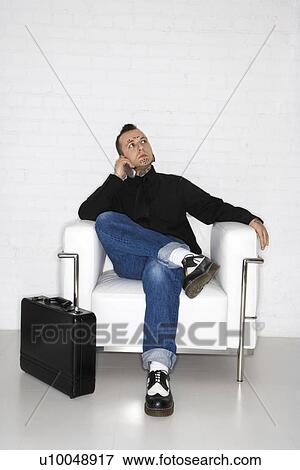 Stock Photo - Caucasian mid-adult man with tattoos and piercings talking on cell phone with briefcase.. Fotosearch