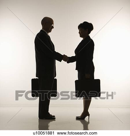 Caucasian middle-aged businessman and Filipino businesswoman standing looking at eachother shaking hands against white background. View Large Photo Image Stock Image - Caucasian middle-aged businessman and Filipino businesswoman standing looking at eachother shaking hands against white background.. Fotosearch