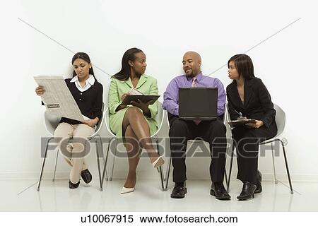Stock Photography - Multi-ethnic business group of men and women sitting looking at laptop and papers.. Fotosearch