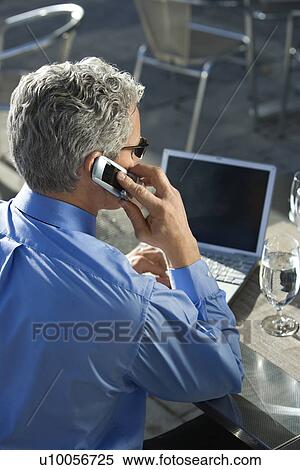 Rear view of prime adult Caucasian man in suit talking on cellphone and looking at laptop. View Large Photo Image Stock Photography - Rear view of prime adult Caucasian man in suit talking on cellphone and looking at laptop.. Fotosearch