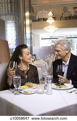 Caucasian mature adult male and prime adult female sitting at restaurant table. View Large Photo Image Stock Photo - Caucasian mature adult male and prime adult female sitting at restaurant table.. Fotosearch