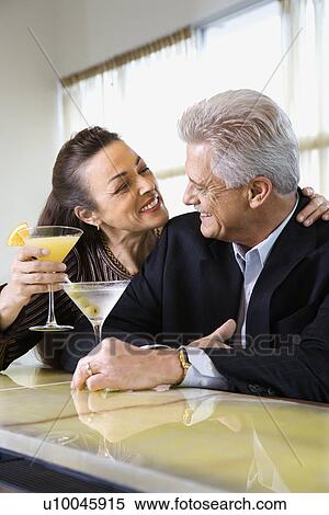 Caucasian mature adult male and prime adult female sitting at bar with cocktails. View Large Photo Image Stock Photography - Caucasian mature adult male and prime adult female sitting at bar with cocktails.. Fotosearch
