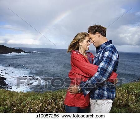 Caucasian mid-adult couple embracing by ocean with rainbow in background in Maui, Hawaii. View Large Photo Image Stock Photograph - Caucasian mid-adult couple embracing by ocean with rainbow in background in Maui, Hawaii.. Fotosearch