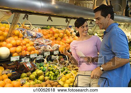 Caucasian mid-adult couple grocery shopping for fruit looking at each other smiling. View Large Photo Image Stock Photo - Caucasian mid-adult couple grocery shopping for fruit looking at each other smiling.. Fotosearch