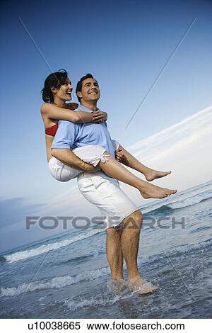 Caucasian mid-adult male carrying female piggyback style on beach. View Large Photo Image Stock Photography - Caucasian mid-adult male carrying female piggyback style on beach.. Fotosearch