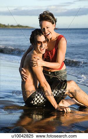 Stock Photography - Caucasian young adult couple frolicking on beach.. Fotosearch