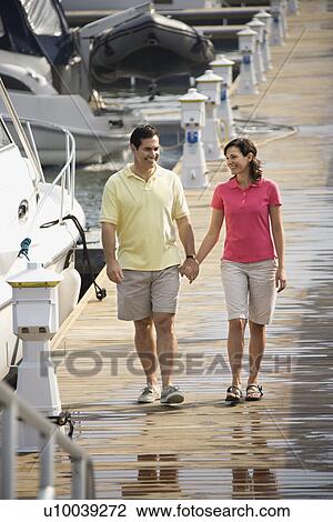 MId-adult Caucasian couple holding hands and walking at harbor. View Large Photo Image Stock Image - MId-adult Caucasian couple holding hands and walking at harbor. . Fotosearch